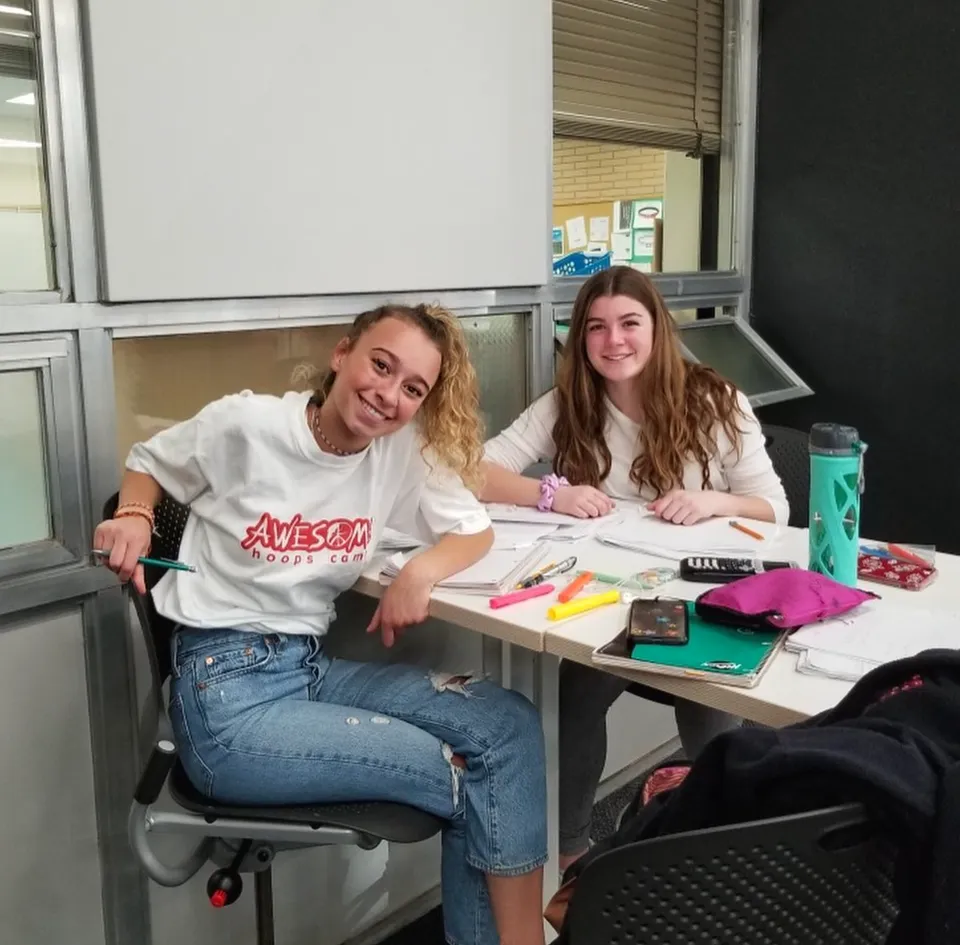 Due studentesse della Henry Wise Wood High School sono sedute a un tavolo e studiano insieme con il materiale scolastico.