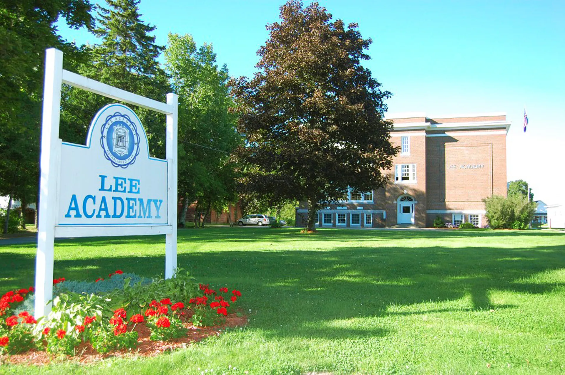 Un cartello con il nome Lee Academy si trova davanti a un edificio in mattoni a più piani nel campus della Lee Academy.