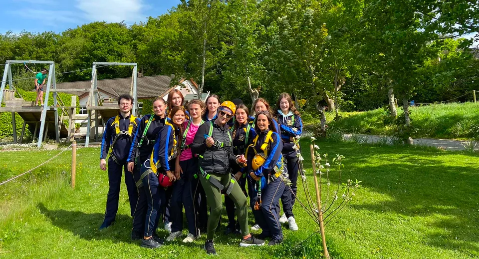 Un gruppo di studenti e studentesse si trova insieme in un'area verde all'aperto nel campus dell'Edmund Rice College.