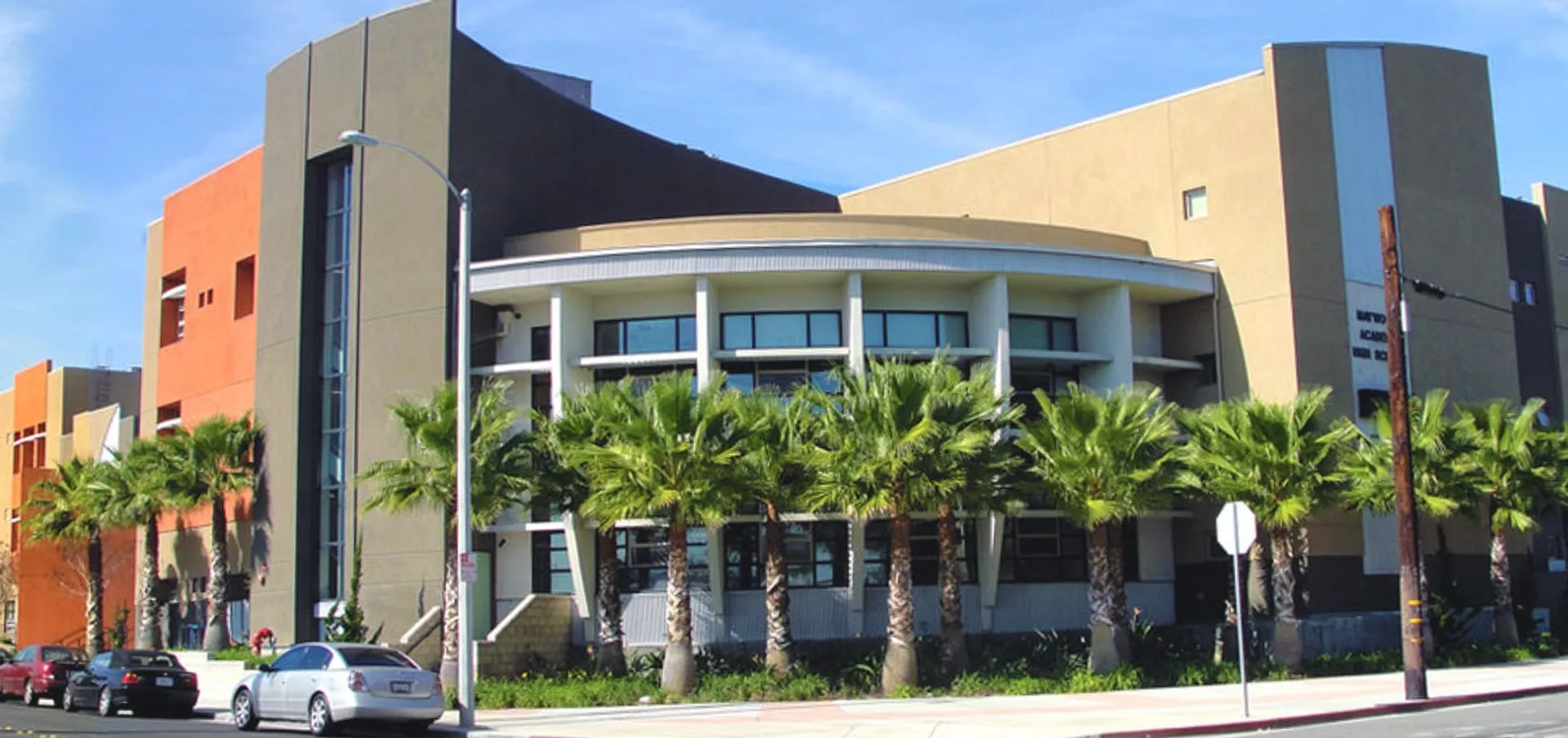 Edificio moderno a più piani con facciata curva e palme nell'area del Los Angeles Unified School District.