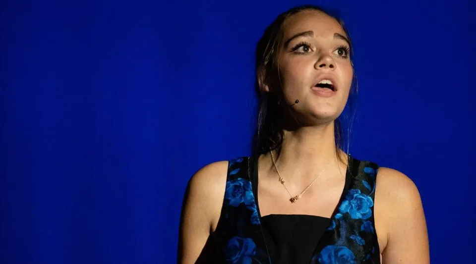 Ritratto di una giovane donna con i capelli scuri davanti a uno sfondo blu nel campus della Andrews Osborne Academy.