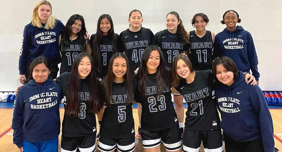 Un gruppo di studentesse della Immaculate Heart Central School in posa con divise da basket abbinate davanti a uno sfondo bianco.