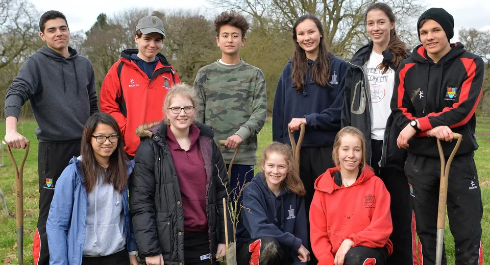 Un gruppo di studenti dell'Ampleforth College si trova insieme all'aperto davanti ad alberi e aree verdi.