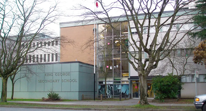 L'edificio in mattoni della King George Secondary School è visibile con alberi spogli in primo piano.