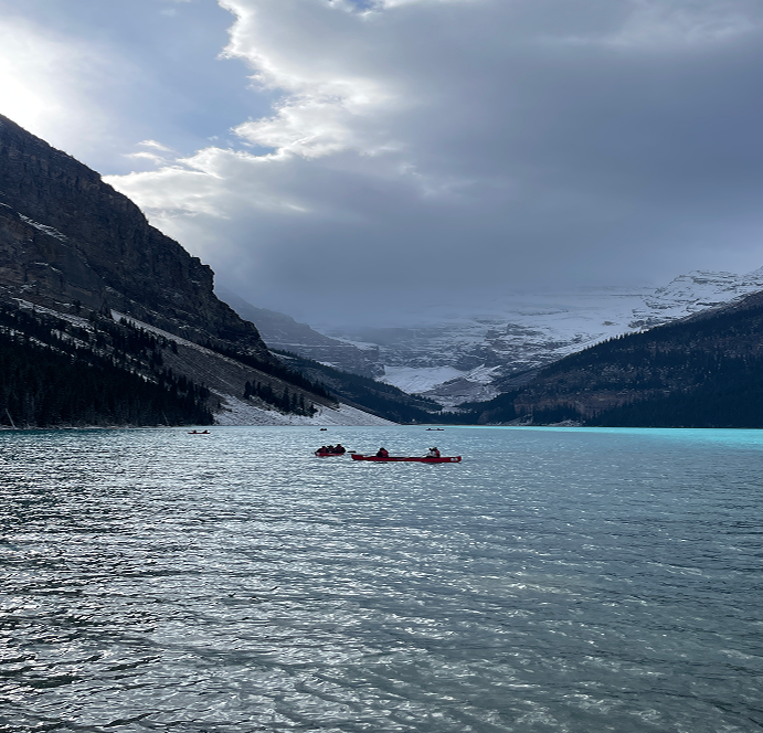 Lago di montagna dalle acque turchesi con canoe e vette innevate sullo sfondo in Canada