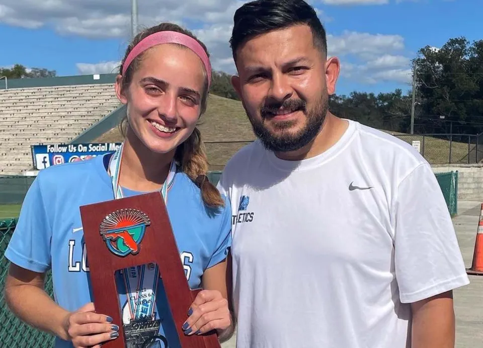 Una studentessa e un insegnante della Lourdes Academy sono insieme davanti a un campo sportivo nel terreno della scuola.