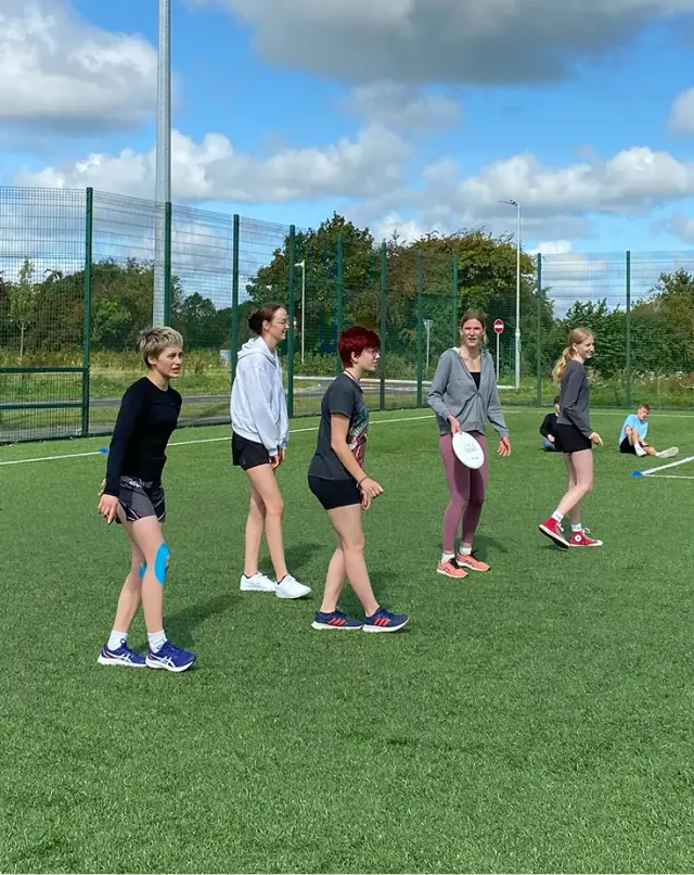 Gruppo di ragazze gioca a frisbee su un campo sportivo in erba