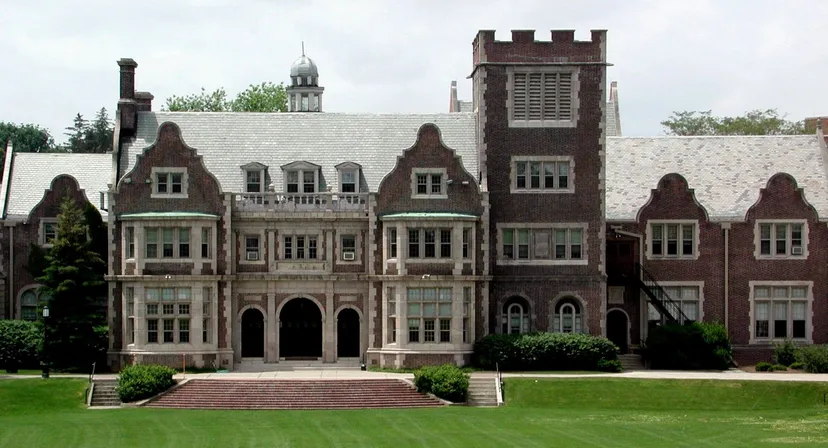Il Hobart College mostra un imponente edificio simile a un castello con torri e finestre ad arco su un ampio prato.