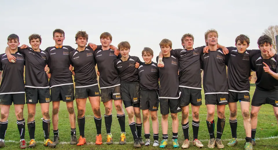 Un gruppo di giovani calciatori è insieme sul campo da gioco della Gresham’s School.