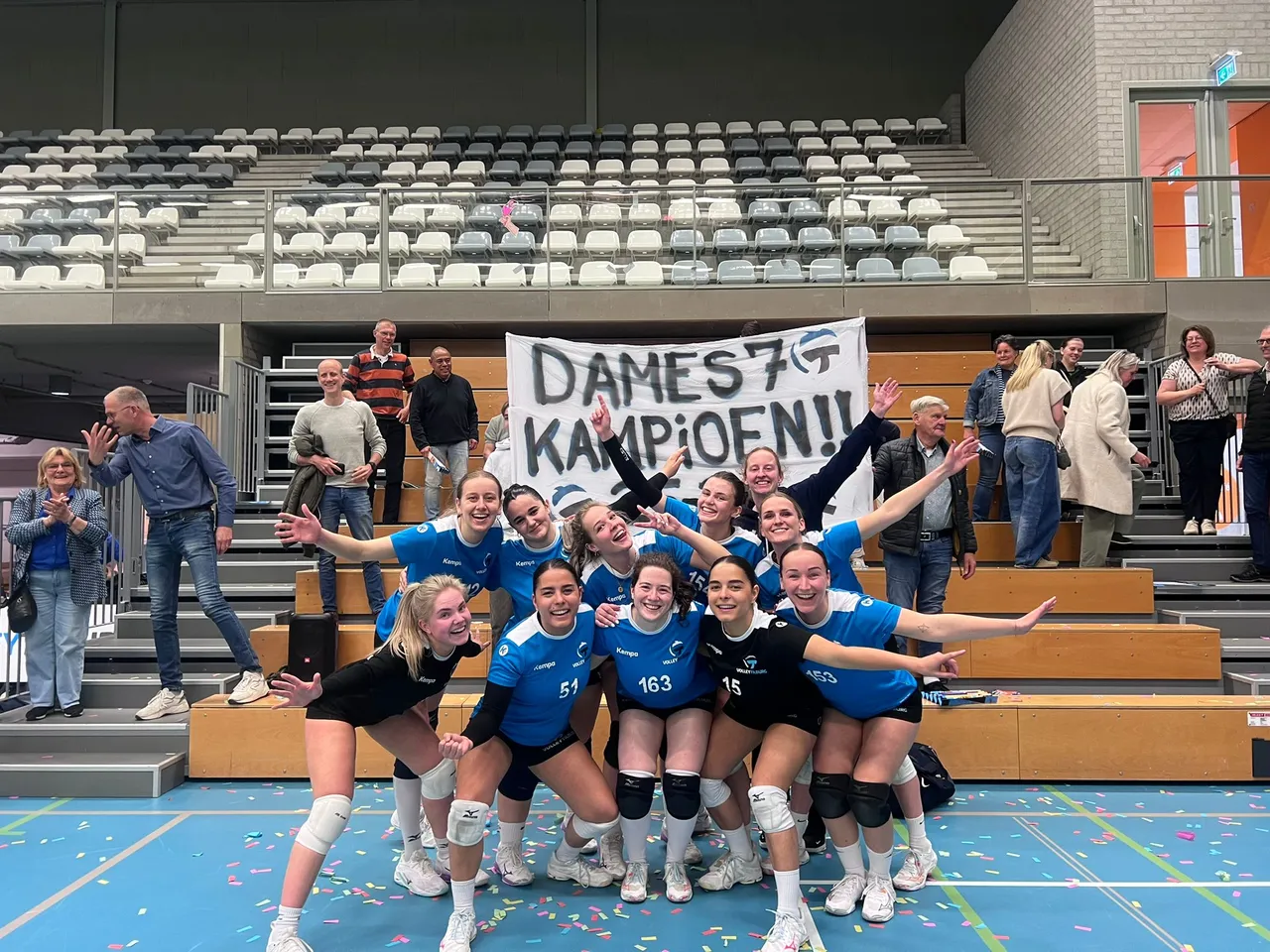 Squadra di pallavolo femminile festeggia il titolo con striscione e coriandoli