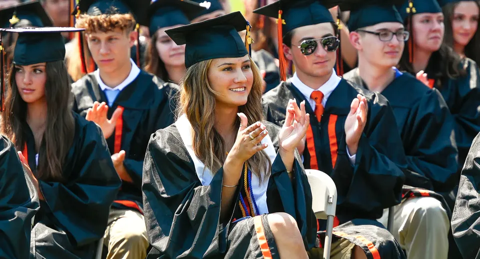 I diplomati della Samuel Robertson Secondary School sono insieme in toga da diploma e sorridono alla fotocamera.