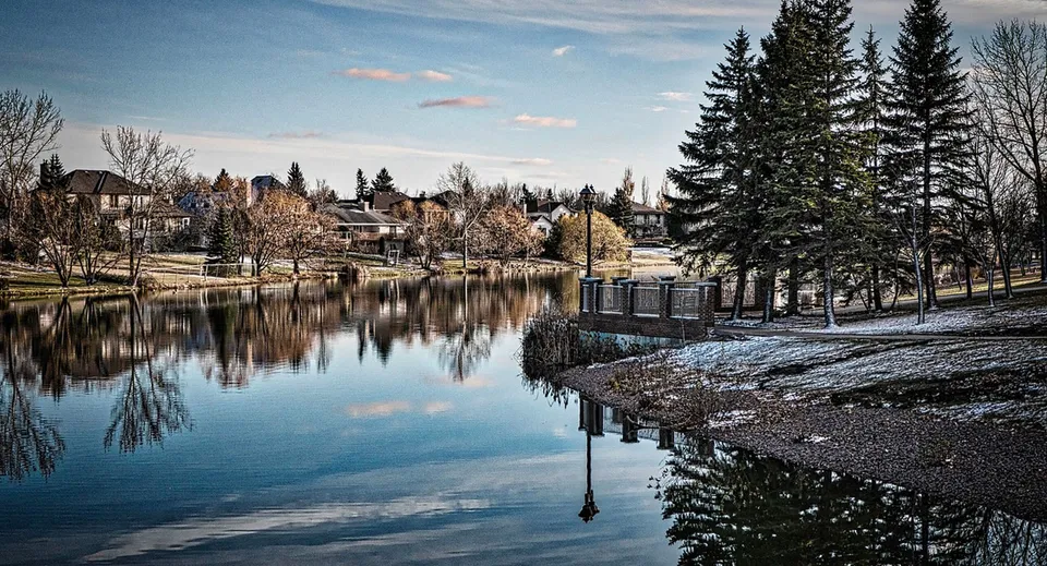 Un tranquillo paesaggio invernale con un lago e pini davanti agli edifici sul terreno del River East Collegiate.