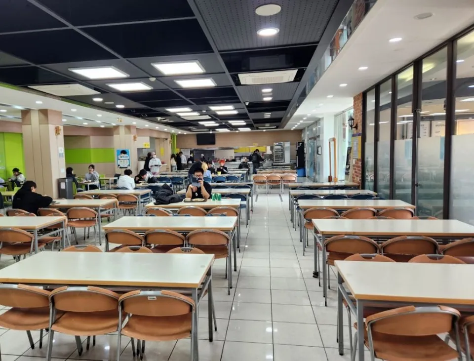 Schüler sitzen an langen Tischreihen in der Mensa der Daekyung Cultural Arts High School.