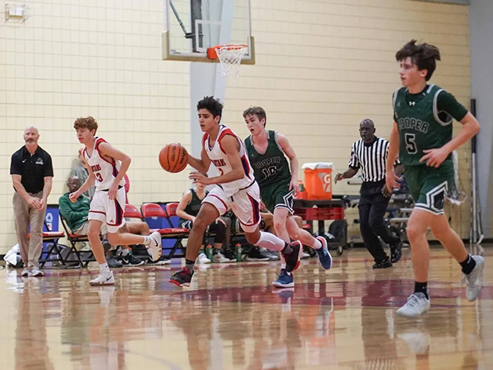 Un giocatore di pallacanestro della St. Stephen's Episcopal School palleggia durante una partita in palestra.