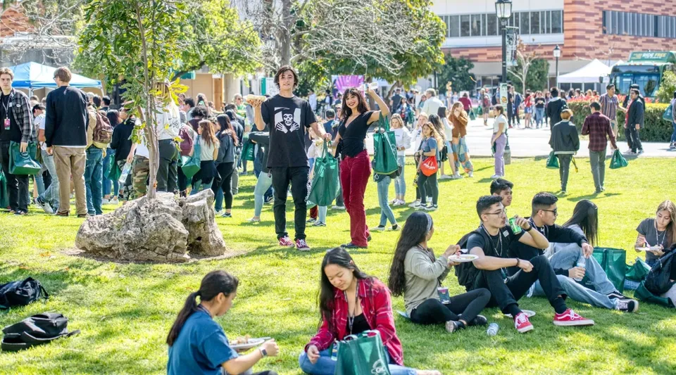 Gli studenti del Golden West College siedono e camminano nella vivace area esterna tra alberi ed edifici.