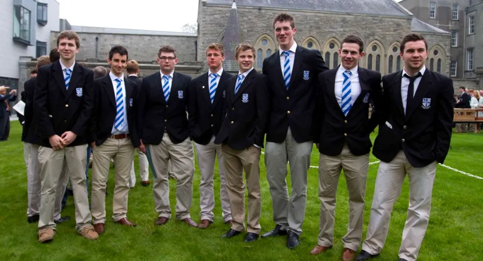Un gruppo di studenti del Blackrock College su un prato davanti a un edificio in pietra.