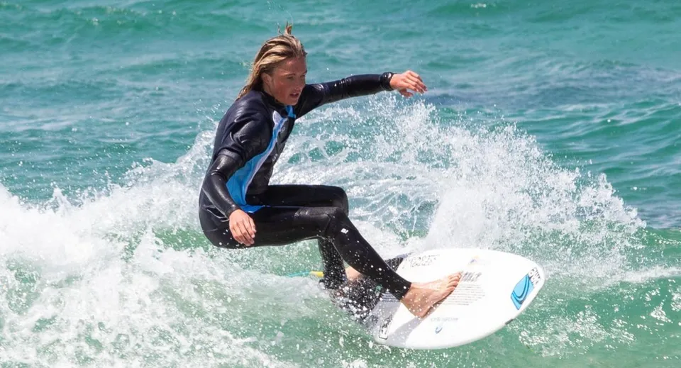 Una persona in muta da sub fa surf su un'onda al largo della costa della Whitsunday Anglican School.