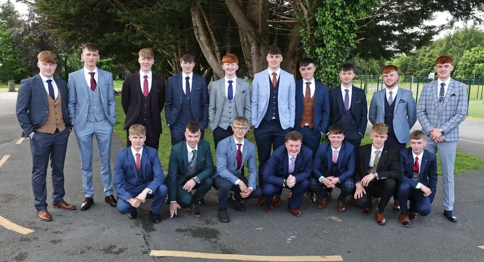 Un gruppo di studenti del St. Coleman's College si trova insieme in un'area simile a un parco con alberi sullo sfondo.