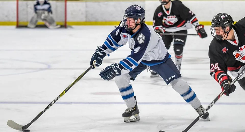 Un giocatore di hockey della Creston Valley Secondary School indossa una maglia bianco-blu e pattina sul ghiaccio durante una partita.