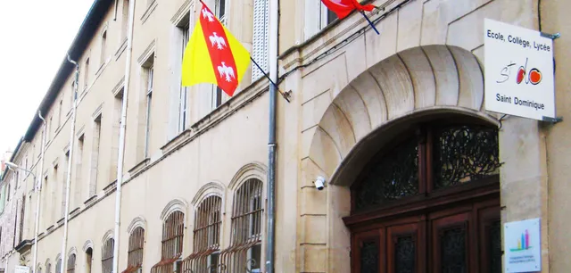 Das historische Gebäude mit Bögen und einer roten und gelben Fahne gehört zum Institut Saint-Dominique.