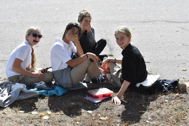 Un grupo de estudiantes de la Immaculata Regional School está sentado en la playa y pasa su tiempo libre juntos al aire libre.
