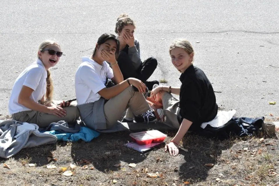 Un gruppo di studenti della Immaculata Regional School siede sulla spiaggia e trascorre insieme il tempo libero all'aperto.