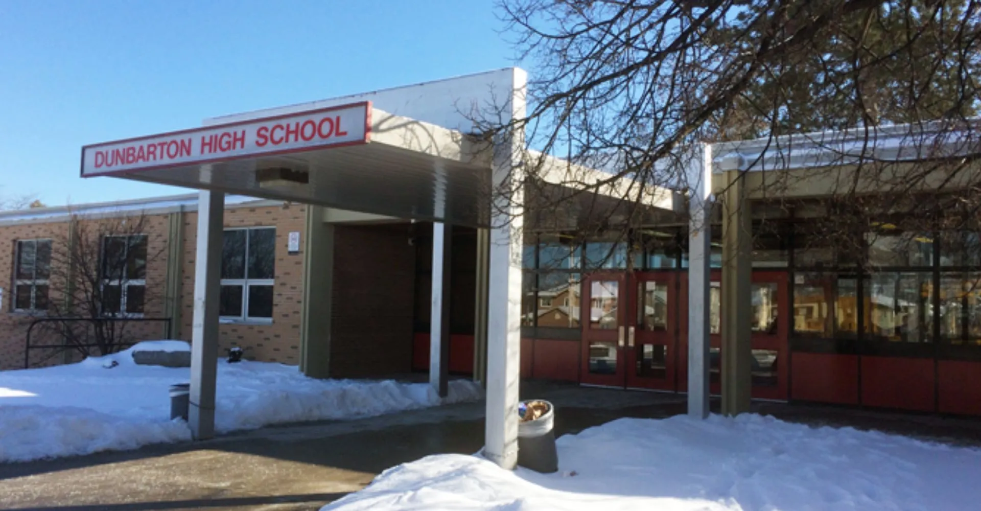 L'ingresso della Dunbarton High School mostra un edificio in mattoni con un cartello davanti ad alberi innevati.