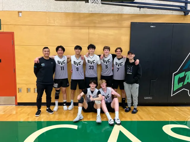 Squadra di pallavolo maschile in maglia SVC posa insieme in una palestra scolastica in Canada
