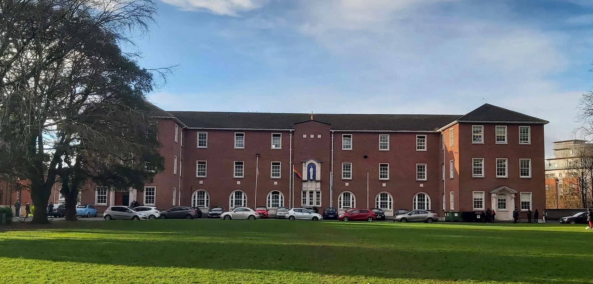 L'edificio in mattoni a più piani con archi nel campus del Marian College sotto un cielo nuvoloso.
