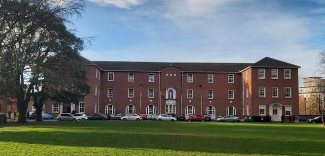 L'edificio in mattoni a più piani con archi nel campus del Marian College sotto un cielo nuvoloso.