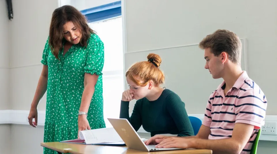 Tre studenti della Rookwood School sono seduti insieme in un'aula e usano un laptop.