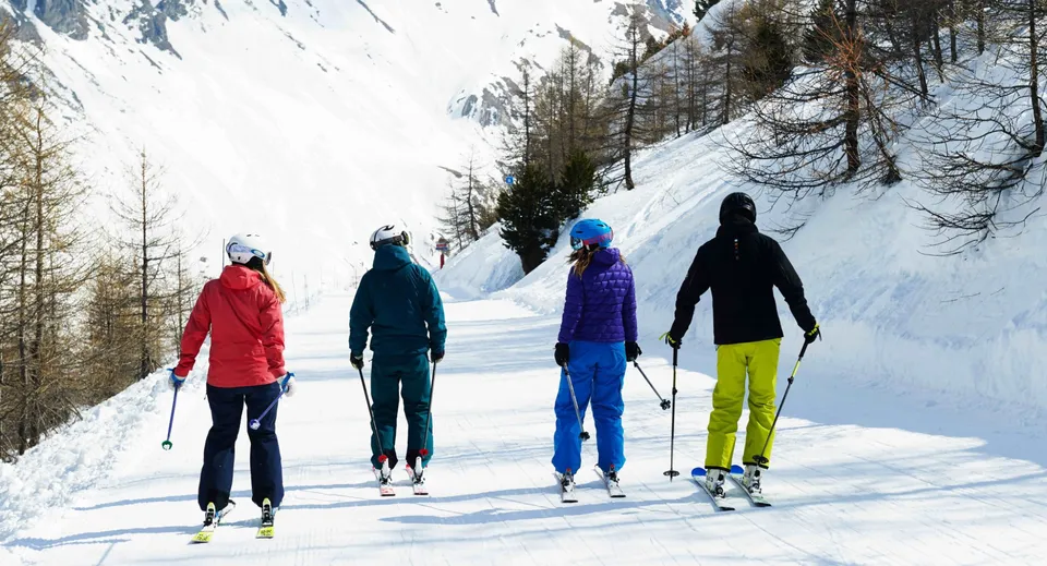 Studenti del Coláiste Muire Crosshaven mentre sciano su un sentiero innevato circondato da abeti e montagne.