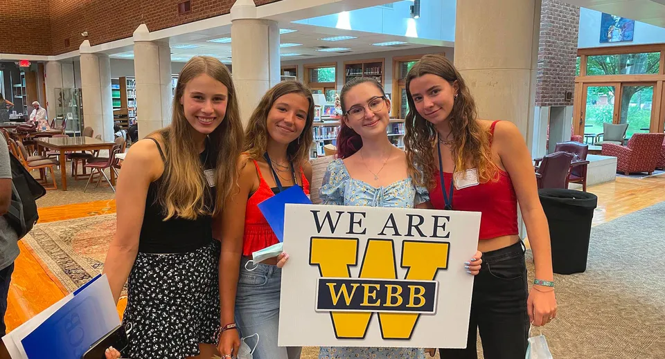 Quattro studentesse della Webb School tengono insieme un cartello con la scritta 'WE ARE WEBB' in un caffè.