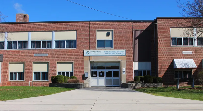 L'edificio in mattoni a due piani della Wallaceburg District High School con grandi finestre si erge sotto un cielo azzurro e limpido.