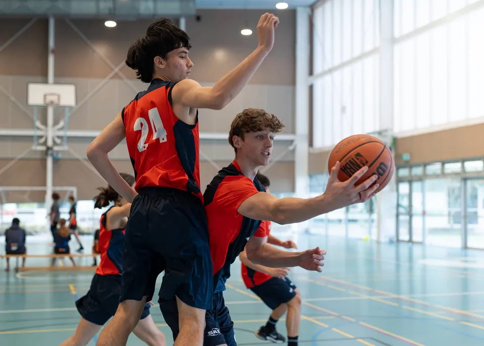 Due giocatori di basket si contendono la palla sul campo da gioco del Papamoa College.