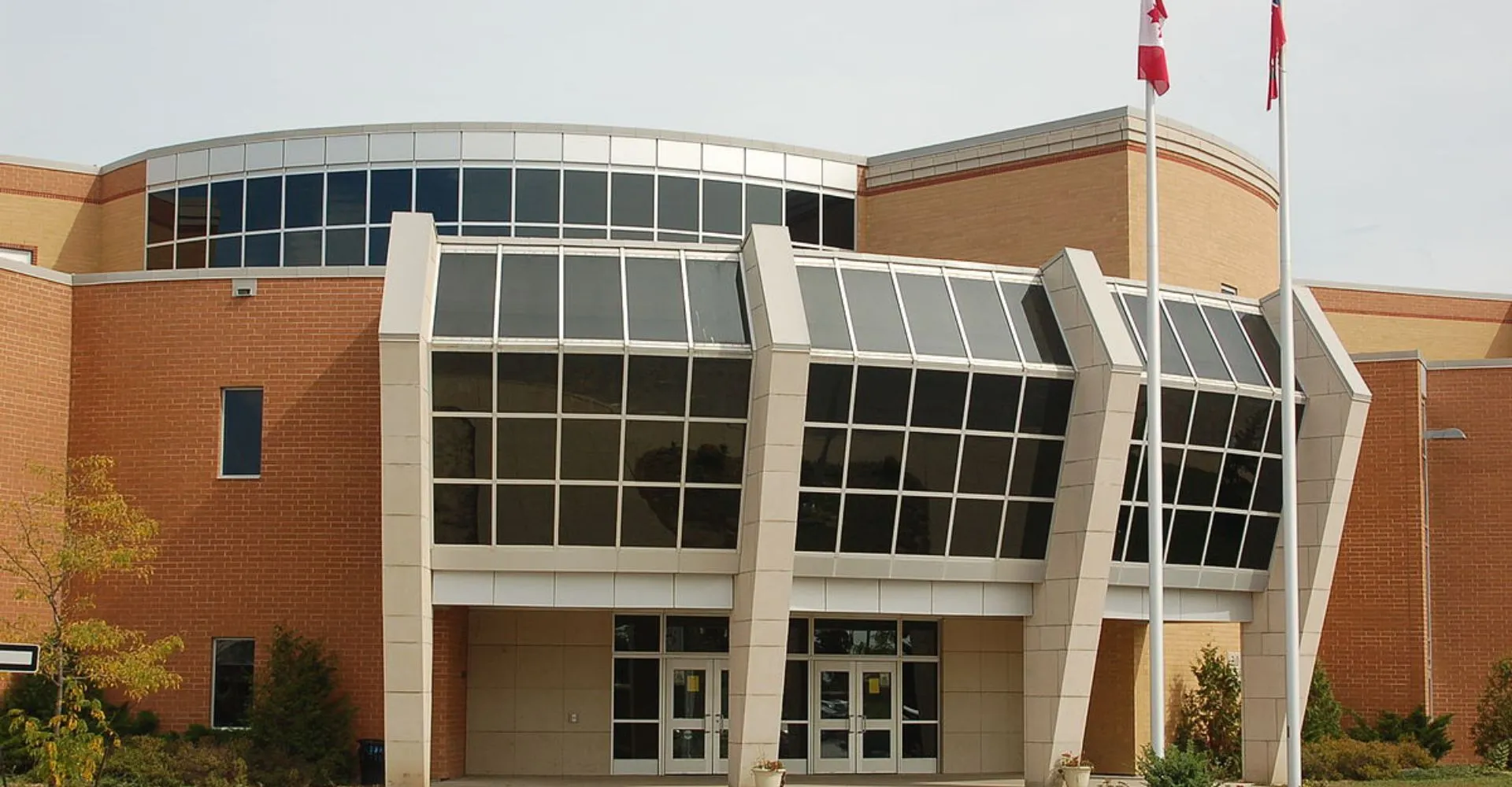 L'edificio moderno a più piani con facciata in vetro del campus della All Saints Catholic Secondary School è circondato da alberi.