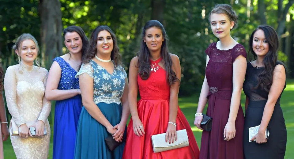 Cinque studentesse della Salerno Secondary School indossano abiti eleganti e si trovano insieme in un'area verde all'aperto.