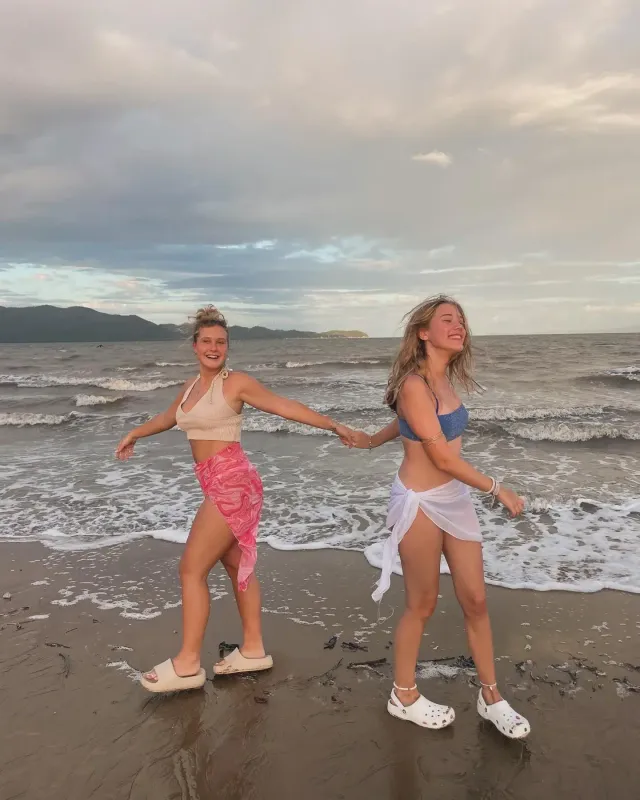 Due amiche mano nella mano che camminano sulla battigia in Australia