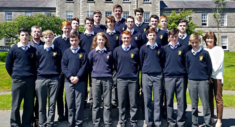 Un gruppo di studenti in uniforme scolastica si trova sul prato davanti a un edificio in mattoni del St. Macartan's College.