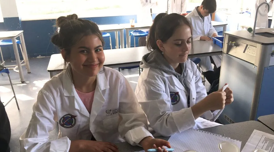 Due studentesse nel laboratorio dell'Our Lady Catholic College indossano camici bianchi da laboratorio e lavorano con apparecchiature mediche.