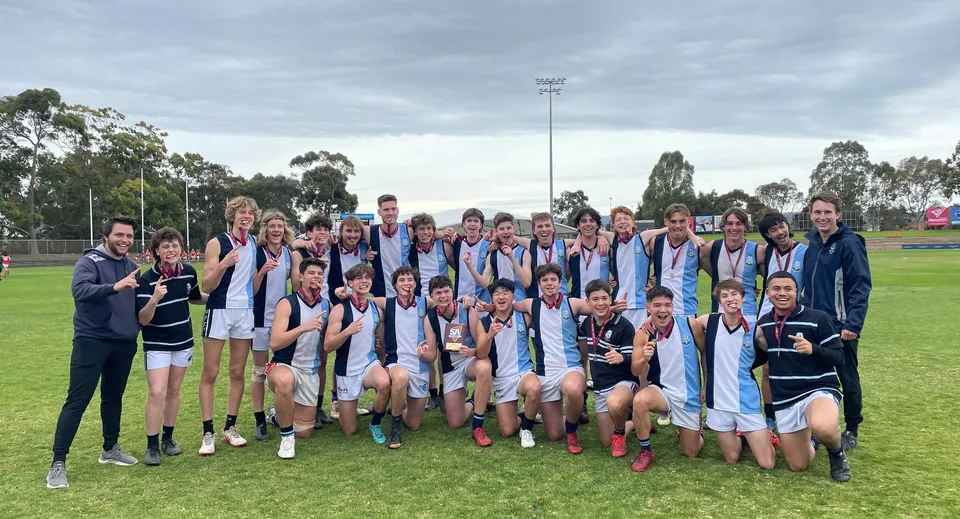 Un gruppo di studenti della Marryatville High School si trova su un campo sportivo con le medaglie in mano davanti a uno stadio.