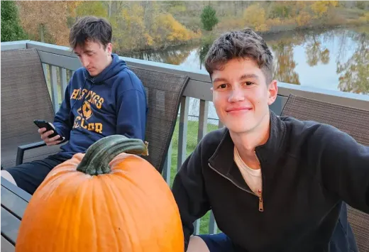 Johannes sorride accanto a una zucca su una terrazza vicino a un lago in autunno negli Stati Uniti