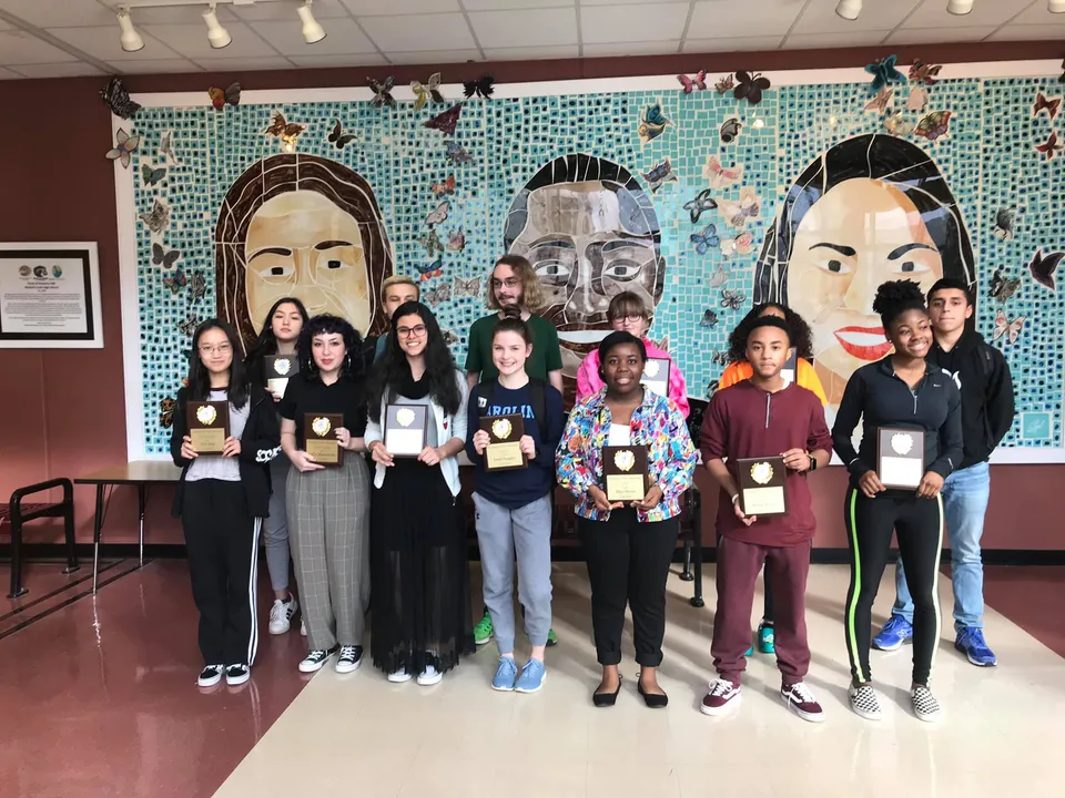 Un gruppo di studenti si trova davanti a un murale colorato nel campus della Mallard Creek High School.
