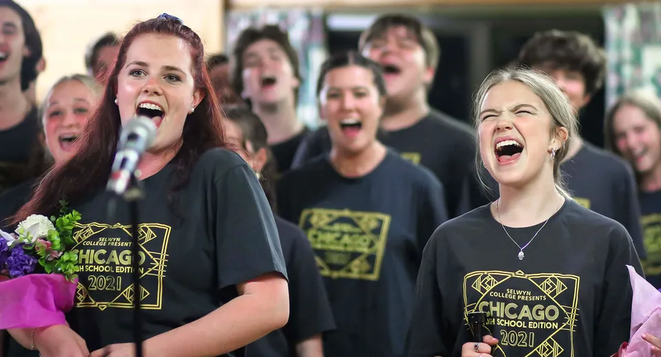 Un gruppo di studenti e studentesse del Selwyn College canta insieme indossando t-shirt nere di Chicago.