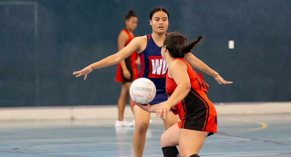 Due studentesse della Hastings Girls' High School giocano a netball: una tiene la palla e l'altra difende.