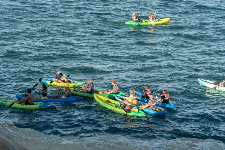 Gruppe von Jugendlichen in bunten Kajaks auf dem Meer