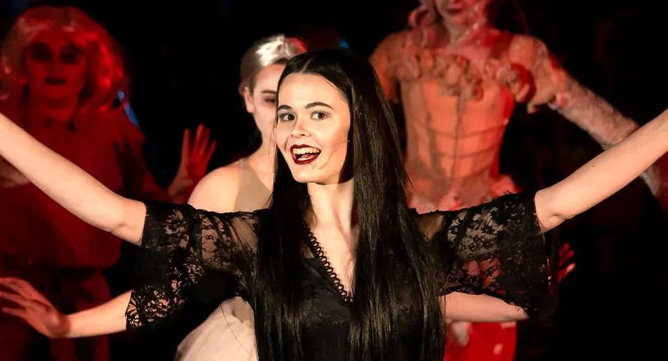 Una studentessa della Ipswich High School esegue una performance di danza con un abito di pizzo nero davanti a un gruppo in costumi rossi.