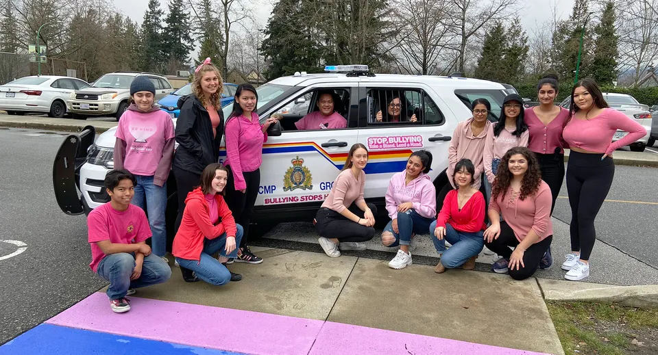 Un gruppo di studentesse della Cariboo Hill School posa all'aperto davanti a un veicolo della polizia.