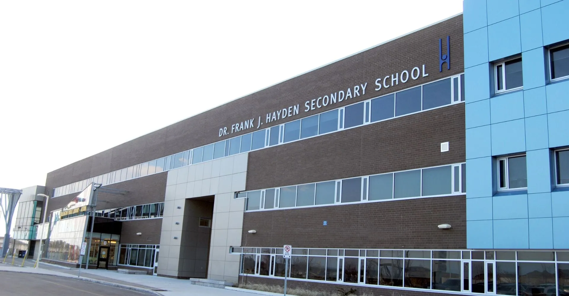 L'edificio scolastico a più piani della Dr. Frank J. Hayden Secondary School con la targa con il nome ben visibile sulla facciata.