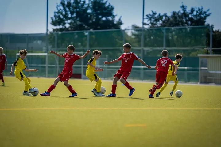 Jugendliche spielen Fußball auf einem Rasenplatz